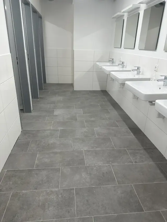 Gereinigter Waschbereich mit Waschbecken, Spiegeln und Fliesenboden